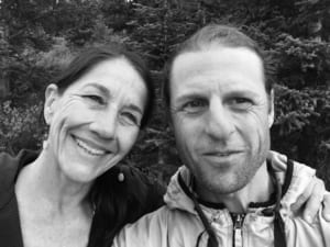 Owners of the Denver Yoga Underground, and primary teachers, Derik Eselius and Brenna Hatami standing in front of a tree in the mountains of Colorado.