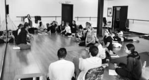 Denver Yoga Underground students sit in a circle and listen to the teacher.