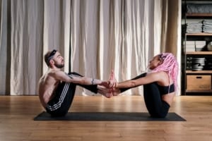 woman with pink hair teaches yoga to a male student