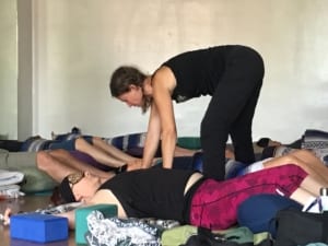 Student receives an assist in a reclined yoga pose