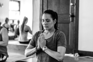 woman meditates with palms joined in a class setting